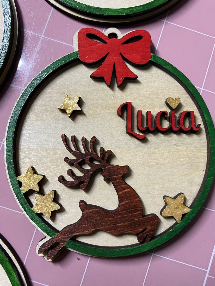 Bola de Navidad personalizada de madera con el nombre Lucía, un reno y estrellas doradas