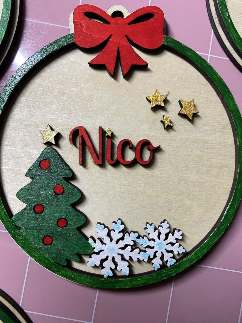 Bola de Navidad personalizada de madera con el nombre Nico, abeto verde y copos de nieve