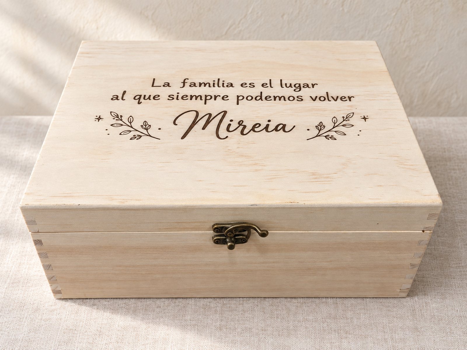 Caja de recuerdos de madera grabada a láser, con la frase «La familia es el lugar al que siempre podemos volver» y el nombre Mireia en la tapa