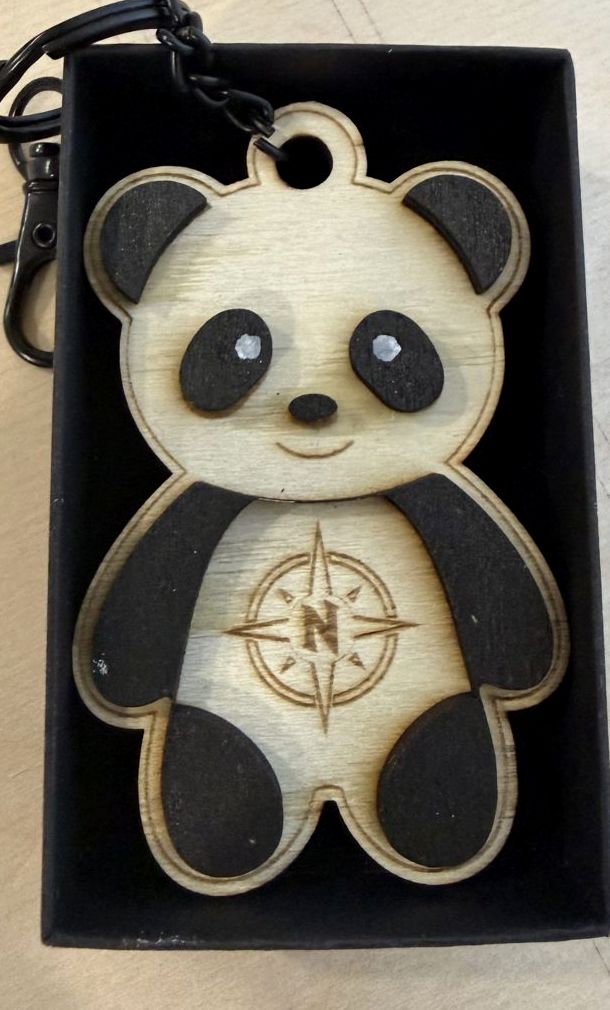 Llavero panda de la colección NORTH, en madera grabada a láser con la brújula en el pecho, dentro de su caja negra